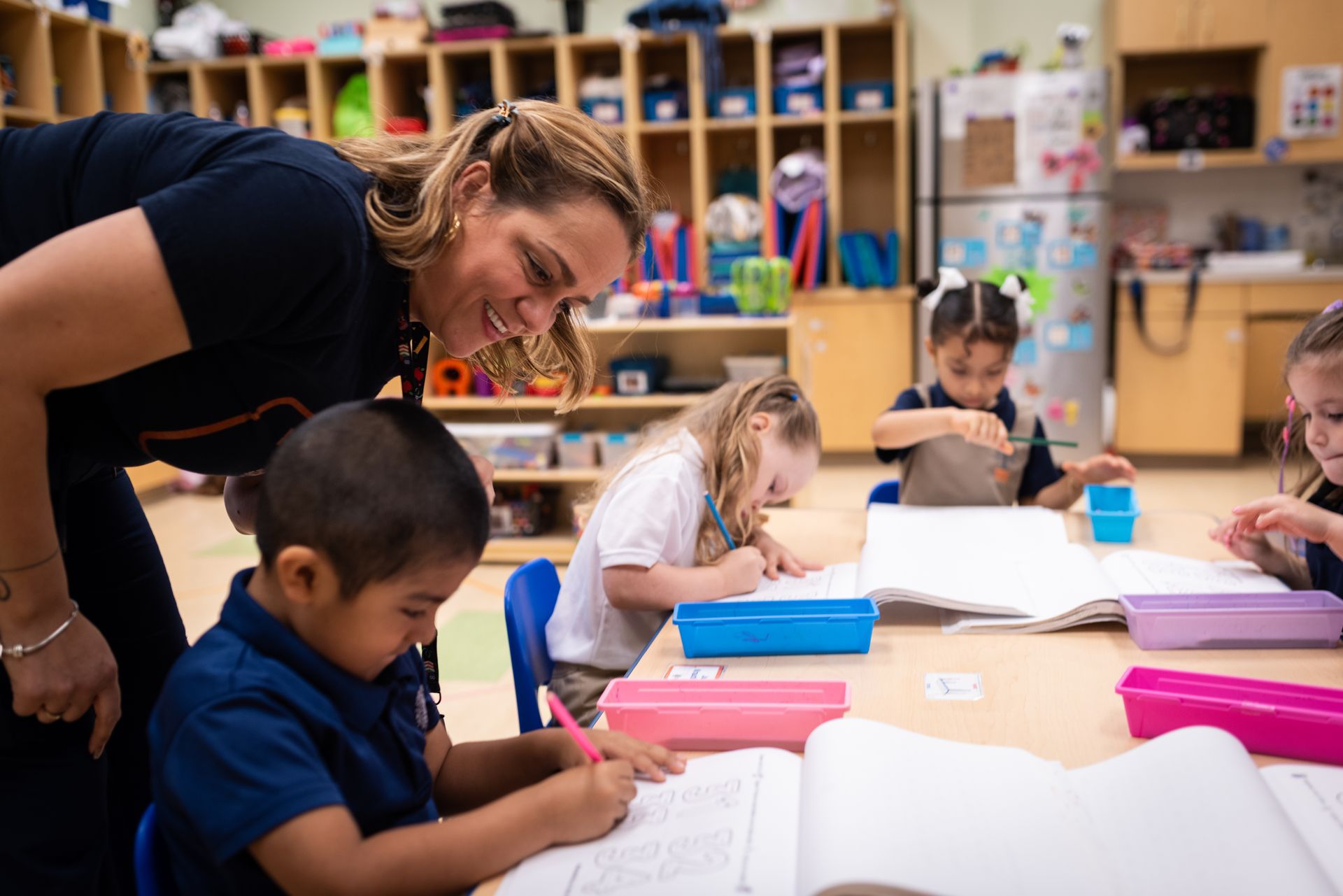 INIC Preschool pre-K teacher guiding a small-group writing activity