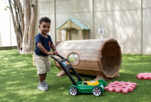 INIC preschool toddler on outdoor lawnmower toy during play